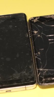 Eski bozuk akıllı telefon. Sarı arka planda akıllı telefonlar. Bozuk ekranlı akıllı telefon. Kırık doku. Dikey video