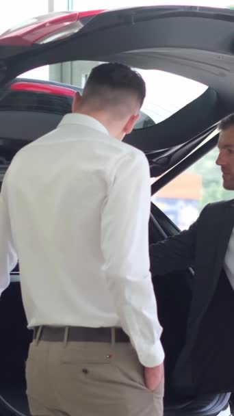 自動車ディーラーのセールスマンは 顧客に新しいSuvを示しています 新しい車を買う 車のトランクの点検 バーティカルビデオ — ストック動画