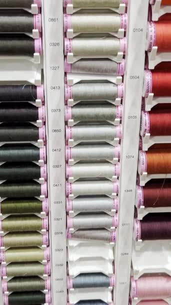 縫製機や家庭用途のさまざまな色の糸のためのスプールの多くの行は 店で販売されています スローモーション バーティカルビデオ — ストック動画