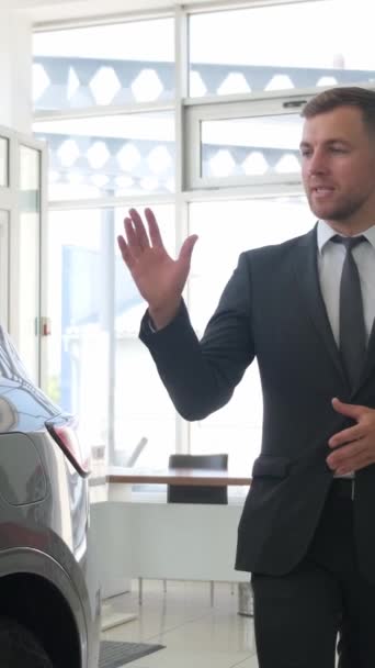 自動車サロンのマネージャーが新車について語る ディーラーの車の販売 バーティカルビデオ — ストック動画