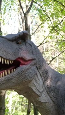 Kocaman dişleri olan korkunç bir dinozorun kafasının büyütülmüş görüntüsü. Dinozor parkına bir gezi. Dikey video