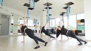 Bir grup genç atletik kız yan kalas pozisyonunda gerinerek yoga egzersizleri yapıyorlar. Spor salonunda çalışan bir grup sporcu..