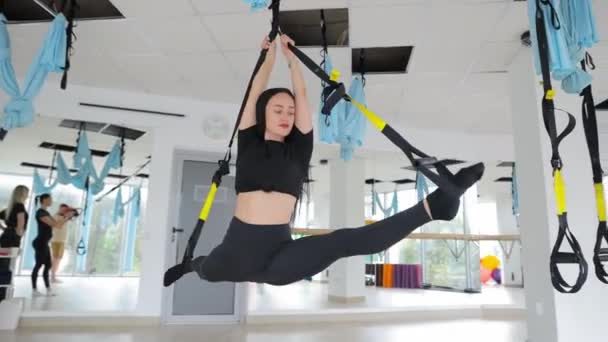 一个漂亮的女孩在吊床上做反重力飞行瑜伽练习 在健身俱乐部进行空中伸展摆动的年轻柔韧女子练习 — 图库视频影像