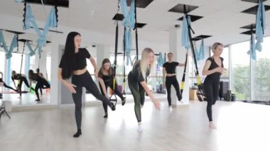 Bir grup genç kadın yerçekimi karşıtı hamaklarda Aero yoga dersi veriyor. Yetişkinler için Jimnastik.