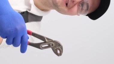 Anahtarı olan bir tesisatçı portresi, gülümsüyor ve baş parmağını kaldırıyor. Tesisat servisi. Dikey video