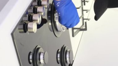 Genç bir tamirci mutfakta bir gaz sobasını tamir ediyor. Gaz sobası tamiri. Dikey video