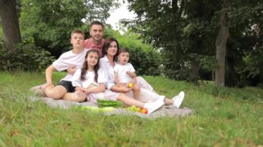 Çocuklu bir aile bahar bahçesinde piknik yapıyor. Aşk, piknik ve aile zamanı gülümseyerek ve ormanda ya da ormanda dinlenerek, sohbet ederek ve eğlenerek. Kamp, dinlenme, yürüyüş..