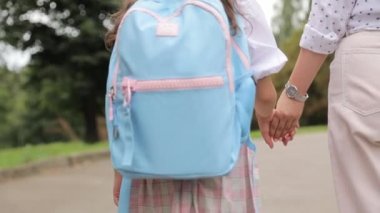 Annesiyle birlikte okula giden küçük bir kız. İlgili bir anne okula yürürken kızlarının elini nazikçe tutar..