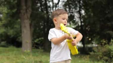 Parkta ukulele çalan sevimli çocuk, kaygısız zihin, müzik konsepti, yaratıcı aktivite, çocuk gelişimi.