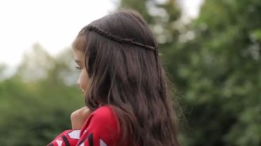 Güzel kırmızı işlemeli elbiseli küçük bir Ukraynalı kız yeşil bir parkta yürüyor. Ukraynalı çocuklar.