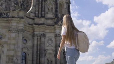 Bir turist kız bir Avrupa şehrinde sırt çantasıyla yürür. Avrupa 'nın güzel mimari yerleri.