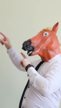 At maskeli bir adam kameraya bakarak dans ediyor. Dikey video.