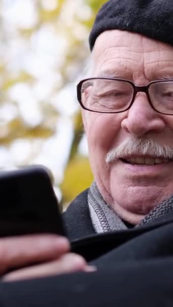 Retrato Anciano Gafas Sobre Fondo Árbol Otoño Sentado Mirando Smartphone — Vídeos de Stock
