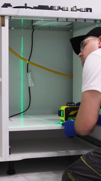 남자는 객실의 부엌에 피팅을 설치하기 정확한 측정을 크로스 레이저 레벨을 — 비디오