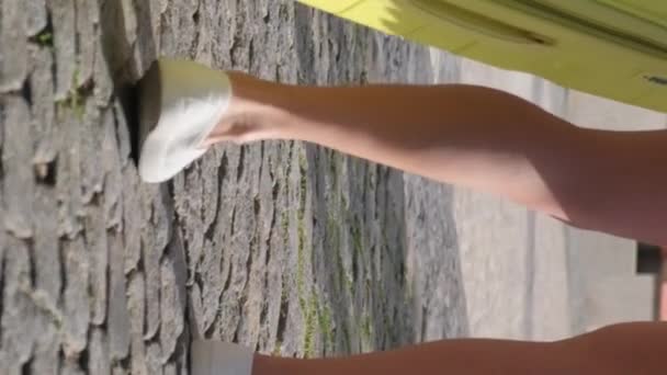 一个带着旅行箱站在太阳光背景下的女人的超级慢动作 镜框里自然的阳光 垂直录像 — 图库视频影像
