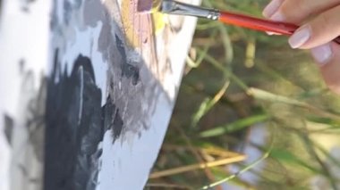 Bir kadın sanatçı gün batımında bir resim çizer. Sanatçı, satılık sanat, doğada ilham. Dikey video.