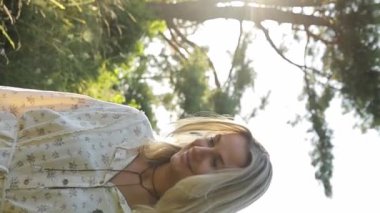 Mutlu kadın gün batımında parktaki rüya portresinde yürüyor. Doğada tek başına dinlenmek. Dikey video.