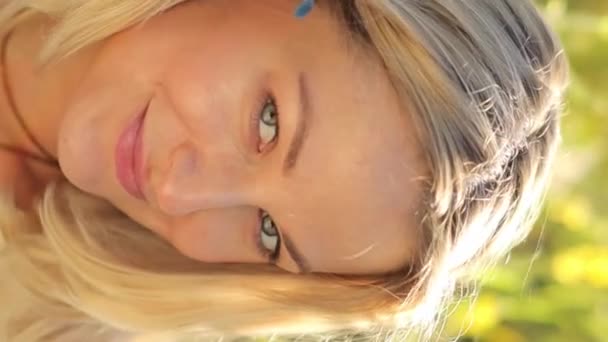 一个漂亮的金发女人看着相机笑的画像 女人在大自然中休息 垂直录像 — 图库视频影像