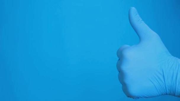 Рука Голубых Перчатках Показывает Большой Палец Изолированный Синем Фоне Человек — стоковое видео