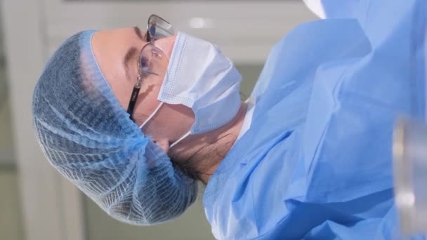 外科医は高齢女性に対して複雑な手術を行います 麻酔下の手術テーブルの患者さん バーティカルビデオ — ストック動画