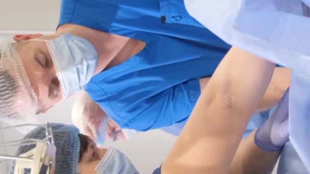 一个熟练的外科团队专注于进行静脉曲张静脉手术来治疗病人的腿状况 垂直录像 — 图库视频影像