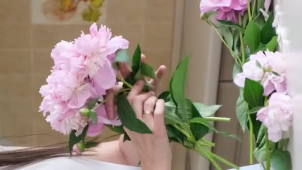 若い女性は自宅で花瓶に美しい花を配置します コニー フラワー 自宅での美しさと快適さ バーティカルビデオ — ストック動画