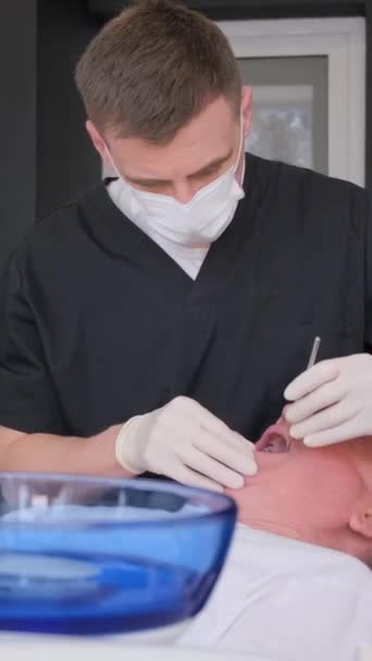 プロの歯科医は高齢者のための入れ歯をインストールします 歯科コンセプト バーティカルビデオ — ストック動画