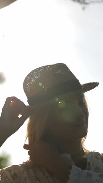 在森林中央的阳光背景下 一个戴着帽子的漂亮女孩的轮廓 慢动作垂直录像 — 图库视频影像
