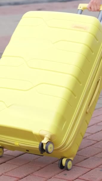 一个难以辨认的女旅行者手拿着一个黄色的手提箱在电车轨道附近的街上走着 旅游广告 垂直录像 — 图库视频影像