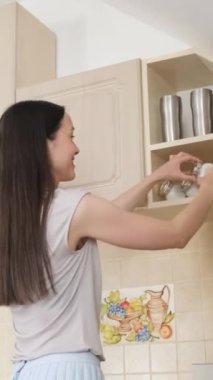 Genel temizlik sırasında modern ev hanımı mutfak dolabını temizliyor. Mutfakta baharatlı, etiketli yemek kileri. Dikey video