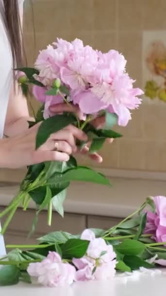 若い女性は自宅で花瓶に美しい花を配置します コニー フラワー 自宅での美しさと快適さ バーティカルビデオ — ストック動画