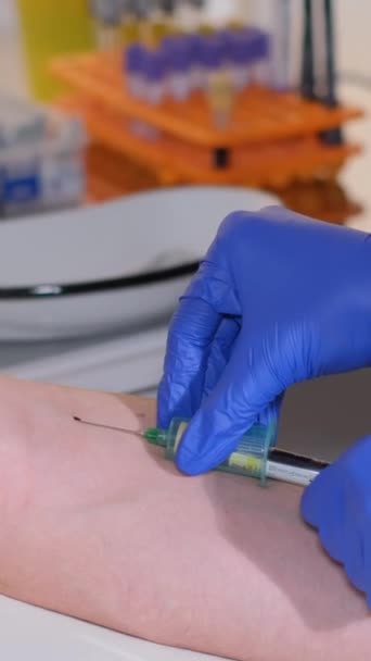 戴手套的护士从病人的静脉中抽血 用针穿刺 供实验室化验用的血样 病人的血液诊断 垂直录像 — 图库视频影像