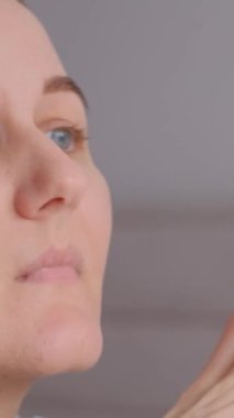 Düşünceli genç bir kadın kanepede oturuyor, uzaklığa bakıyor, düşünüyor ya da düşünüyor, özel hayatında sorunlar yaşıyor. Dikey video.
