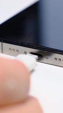 Adamın biri akıllı telefonu şarj etmek için kabloyu bağlıyor, yakın plan. Dikey video.