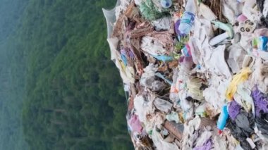 Güzel dağların ortasında büyük bir çöp yığını, plastik atık çöplüğü. Ekolojik felaket, zehirli atık. Dikey video