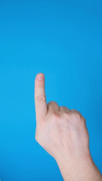 男性的手把一个手指指向侧面 做一个手势 用蓝色背景隔开 在蓝色背景上孤立的手势 垂直录像 — 图库视频影像