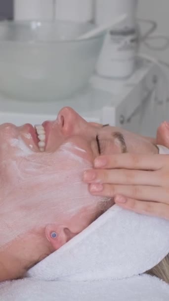 화장품 전문가는 엘리트 살롱의 선반에 누워있는 여성의 얼굴을 마사지합니다 적절한 — 비디오