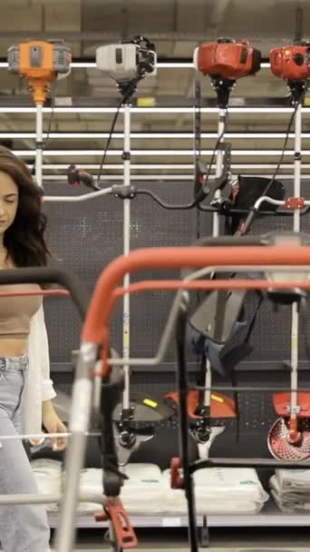 여자는 하드웨어 상점에서 기계의 거대한 선택의 자신의 마당을 돌보는 비디오 — 비디오