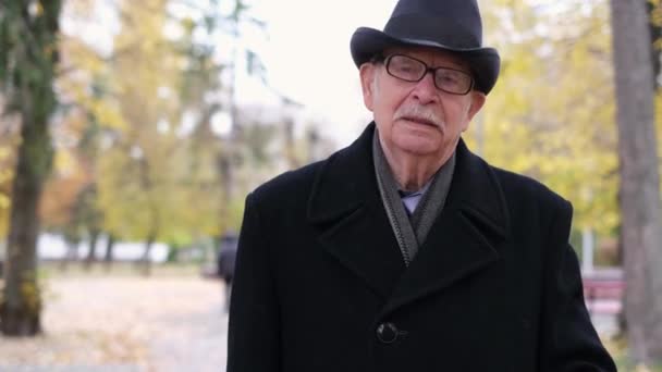 Der Senior Spaziert Durch Den Herbstpark Trägt Einen Schwarzen Mantel — Stockvideo