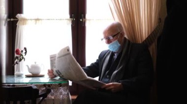 Yaşlı bir İtalyan beyefendi bir kafede oturuyor, bir sandalyede, kahve içiyor ve basını okuyor..