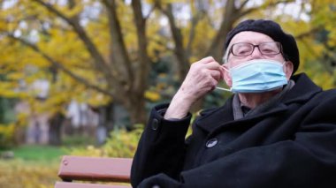 Yaşlı bir büyükbaba sokakta koruyucu bir maske takıyor. Solunum hastalıkları, grip ve soğuk algınlıkları.