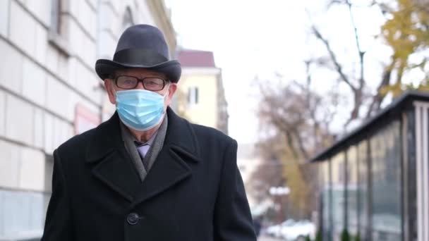 爷爷走在城市的街道上 他戴着防护面具 警惕病毒感染 老年人的保健 — 图库视频影像