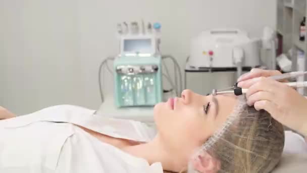 美容師の美容師は マイクロ電流治療装置で顔に手順を行います クライアントのためのクリニックサロンのハードウェア化粧品 — ストック動画