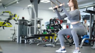 Spor salonunda çömelme egzersizi yapan güzel bir kız. Crossfit eğitimi. Dikey video