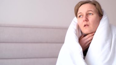 Sağlıksız bir kadının yatakta oturup öksürmesinin yanı sıra grip, yüksek ateş ve baş ağrısı, sağlık hizmetleri..