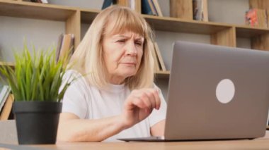 Evde dizüstü bilgisayar kullanarak çalışmaktan yorgun düşmüş. Yaşlı bir kadın, sağlık sorunları, görme bozukluğu. Dizüstü bilgisayarın önünde çalışmaktan yoruldum.. 