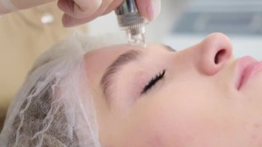 Bir güzellik uzmanı genç bir kadının yüzündeki deriyi muayene eder. Genç bir kız, kozmetoloji uzmanına yaptığı ziyarette profesyonel yardım alır..