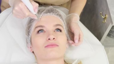 Kozmetoloji kliniğinde bir kozmetik uzmanıyla randevusu olan bir kız, bir dermatolog bir hastanın cildine masaj yapar ve bir müşteriye danışır, kozmetoloji kavramı....