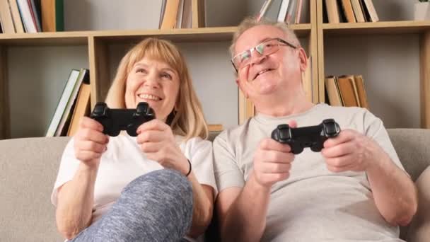 Happy Elderly Couple Sitting Sofa Home Playing Games Holding Joysticks — Stock Video