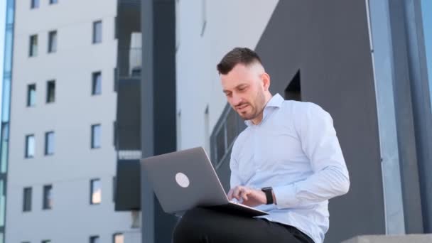 Молодой Бизнесмен Работает Интернете Ноутбуком Сидя Скамейке Возле Своего Офиса — стоковое видео